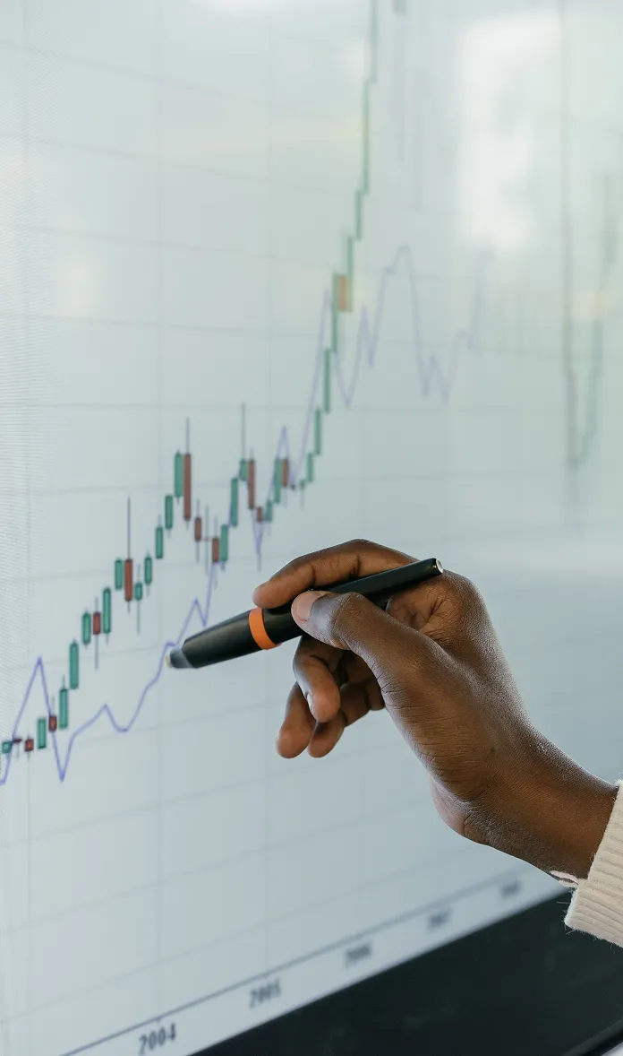 Hand pointing at a financial chart on a digital display